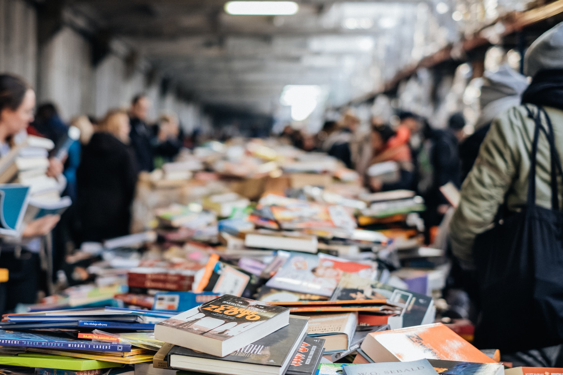 Several books on different tables with readers picking them up