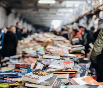 Several books on different tables with readers picking them up